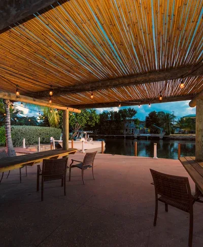 Waterfront tiki hut dining area with fire pit and canal views